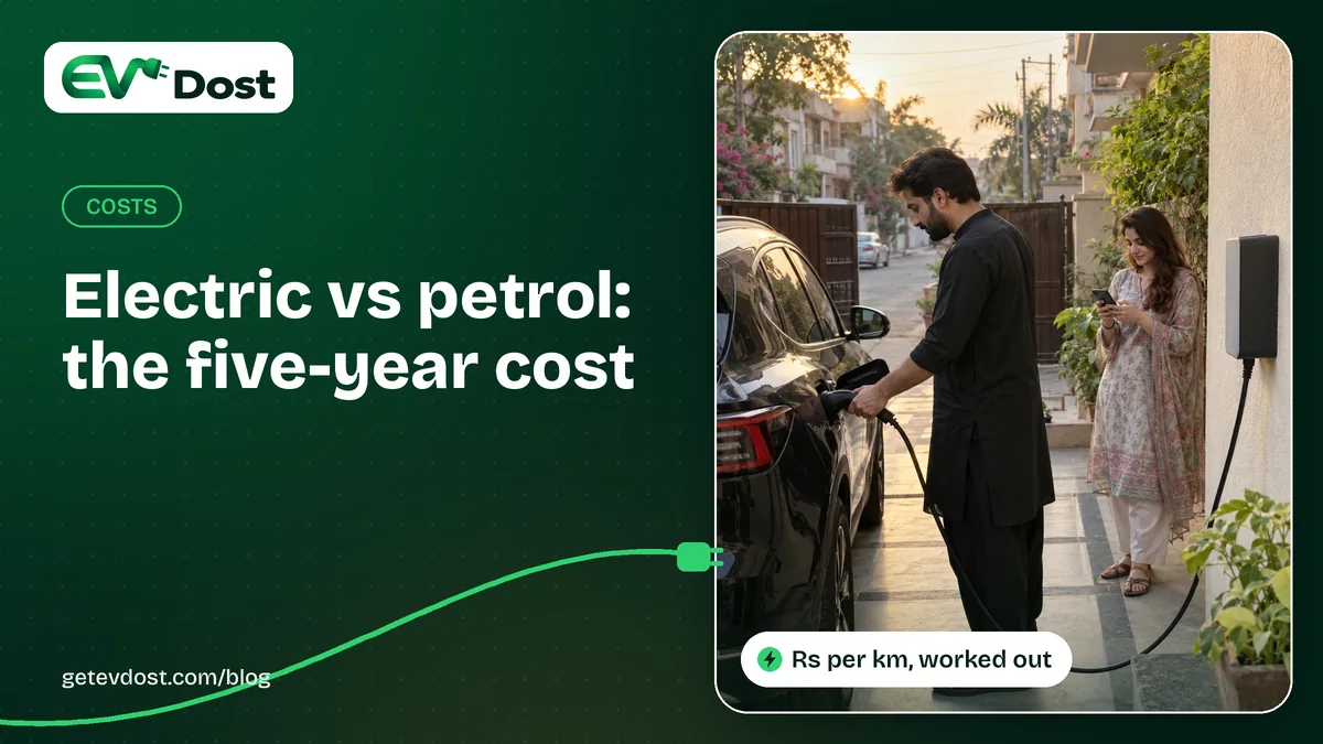 A man plugs in his black car at a wall charger on a tree-lined street at golden hour while a woman checks her phone nearby