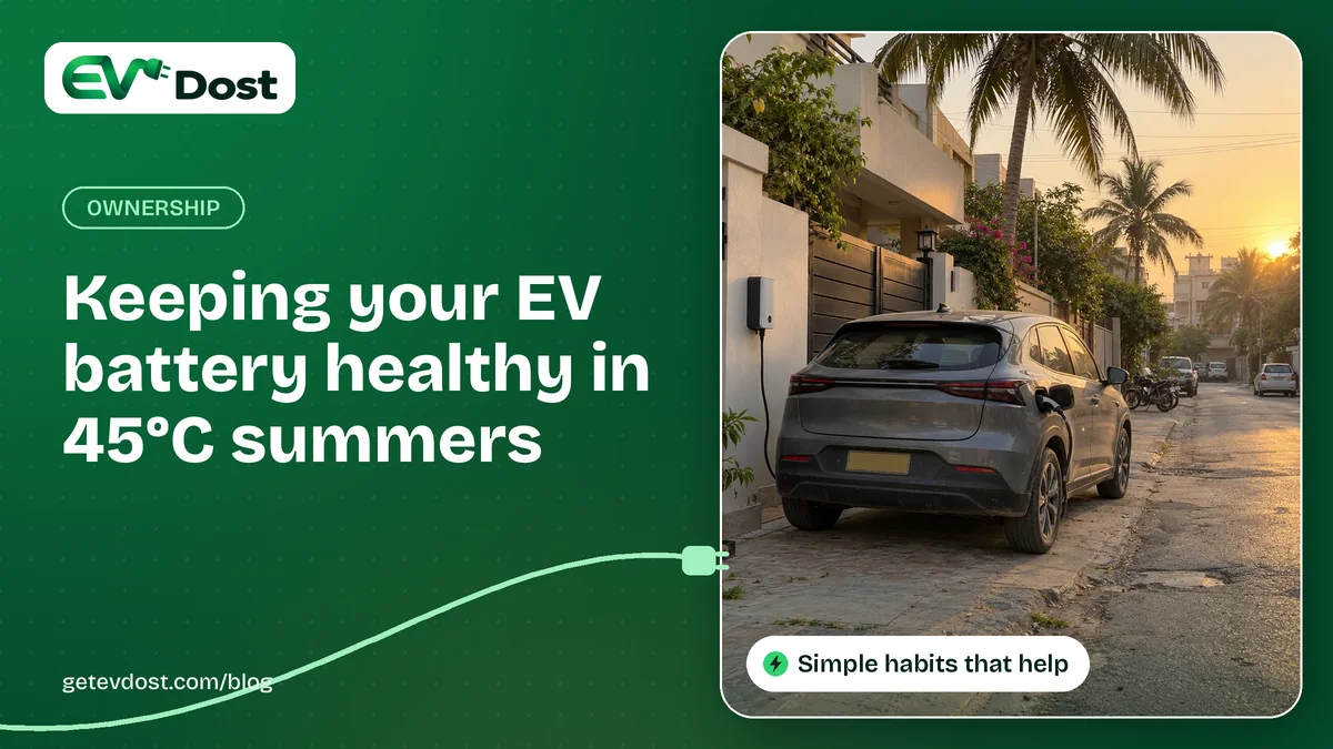 A grey electric car charges from a wall-mounted charger on a palm-lined street at golden hour