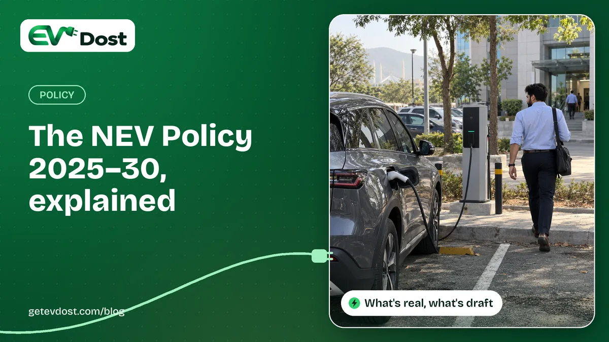 A man in office clothes walks towards an office building while his grey electric SUV charges at a post in the car park
